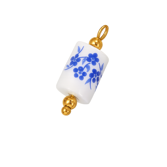 A white cylindrical pendant charm with a blue floral pattern and gold-tone metal accents, shown on a plain white background.