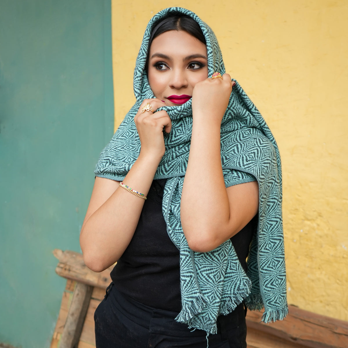 Turquoise and charcoal Ecuadorian alpaca scarf worn over the head and shoulders, Alennya.