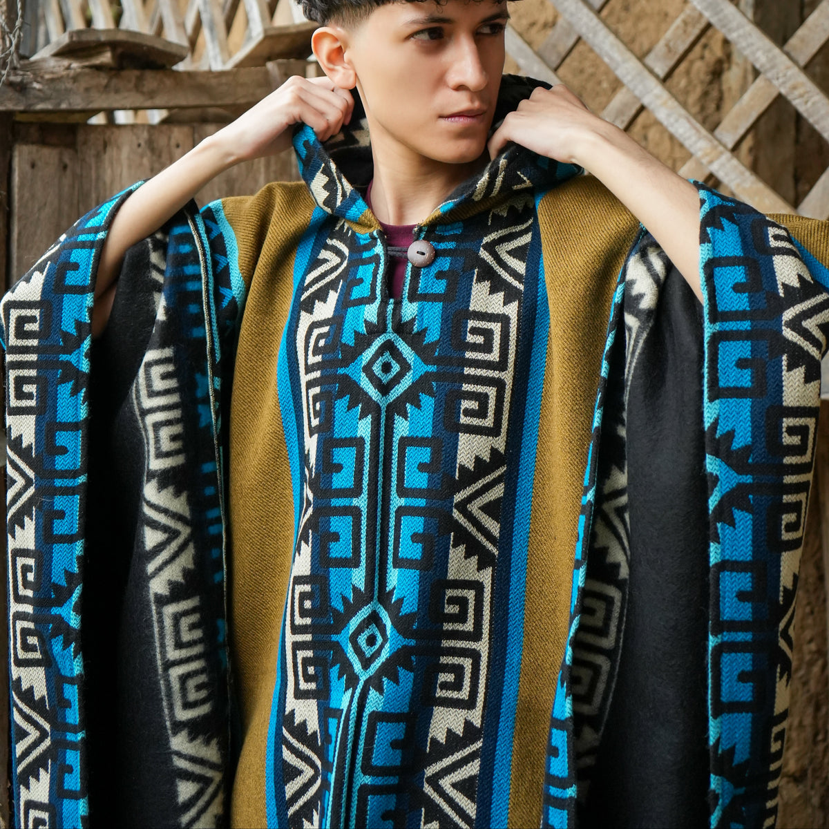 Turquoise and mustard Ecuadorian alpaca poncho with hood, worn outdoors, Alennya.